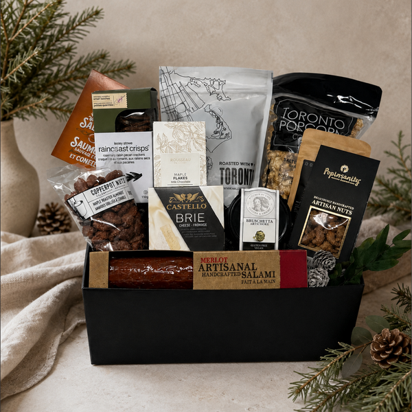 A gourmet shareable gift basket filled with assorted Canadian snacks, cheeses, and treats in a black rectangular box.